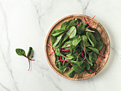 Fresh salad of green chard leaves on white marble background