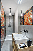 Shower, washstand and exposed brickwork in narrow bathroom