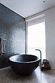 Freestanding oval bathtub against a shimmering mosaic wall