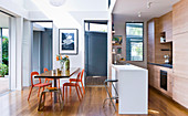 Dining table with orange chairs in front of open kitchen with counter