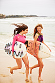 Zwei Frauen in Bikinis und mit Surfboards am Strand