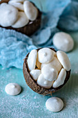 Meringue from aquafabs in a coconut shell on a blue background