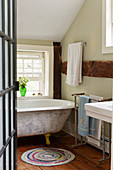 Old, free-standing bathtub in rustic bathroom with wooden beams