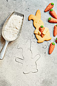 Easter Bunny biscuits with marzipan carrots and a scoop with flour