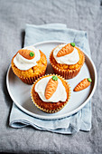 Carrot muffins topped with cream cheese frosting and marzipan carrots