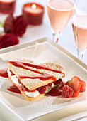 Romantic dessert for two on Valentine's Day with heart shaped shortbread sandwiched with cream and raspberries