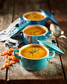 Carrot and orange soup served in three small soup tureens