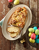 A bread plait with flaked almonds and coloured Easter eggs in a wire basket