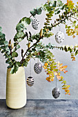 Easter eggs decorated with geometric patterns hanging on twigs