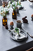 Gedeckter Tisch zum Osterfrühstück mit gekochtem Ei, Kaffee und Schokoladenhase