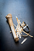 Horseradish root, partially peeled next to a peeler