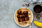 Sliced freshly baked dark chocolate banana bread cake dessert in plate over grey concrete table background