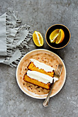 Flat-lay of sliced freshly baked lemon cake dessert with mascarpone cream in plate over grey concrete background