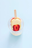 Strawberry and custard popsicle melting in a glass