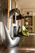 Silver seat and green satin acrylic seat in room with mounted moose and zebra heads