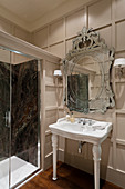 Französisches Porzellan-Waschbecken unter verziertem Spiegel im getäfelten Badezimmer