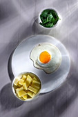 A fried egg served with salted potatoes and spinach