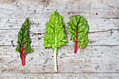 Three chard leaves on a wooden surface