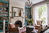 Turquoise bookcases flanking fireplace in English-style living room
