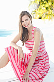 A young woman wearing a striped summer dress by a pool