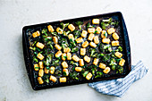Green broccoli and roasted tater tots casserole topped with grated parmesan cheese and black pepper