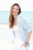 Junge Frau in weißem Top und hellblauem Hemd am Meer