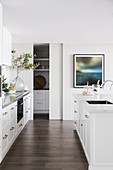 Glance into bright contemporary kitchen with white kitchen unit and kitchen island