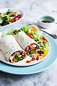 Vegan burrito with vegetables and wild rice, drizzled with oil chilli sauce