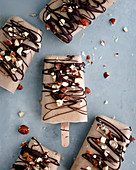Banana and peanut butter ice cream sticks with chocolate and chopped nuts