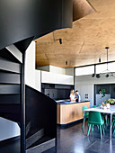 Black spiral staircase in architect's house with open kitchen
