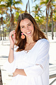 A brunette woman outside wearing a white blouse