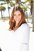 A brunette woman outside wearing a white blouse