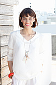 A brunette woman wearing a white long-sleeved blouse