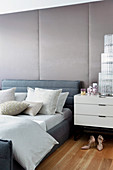 Graues Polsterbett vor gepolsterter Wand im glamourösen Schlafzimmer