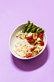 Chicken bowl with asparagus, rice, tomatoes and passion fruit sauce