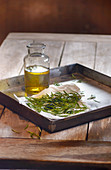 Rosemary oil and fresh rosemary on a metal tray