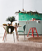 Round table with chairs and green tiles above base cabinet in kitchen decorated for Christmas