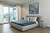 Bed with upholstered frame in minimalist bedroom in grey and blue