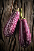 Two purple striped aubergines on a wooden background
