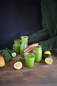 A green smoothie with ingredients on a rustic wooden table