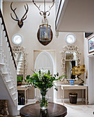 Foyer decorated with antlers and ornate mirrors above console tables
