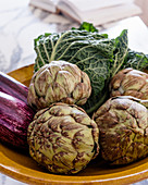 Fresh artichokes, aubergines and Savoy cabbage in ceramic bowl