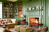 Open fireplace in library with green wooden panelling in renovated English manor house