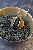 Mao Feng, green tea from China with a tea strainer in a bowl