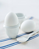 Frühstücksei im Eierbecher auf blau-weiß gestreifter Stoffserviette
