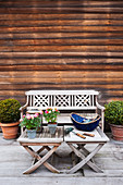 Sitzbank und Tische vor Holzfassade auf geräumiger Terrasse