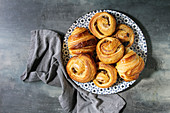 Variety of homemade puff pastry buns, cinnamon rolls and croissant served in ceramic plate