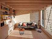 Sofa and shelves in modern living room with brick wall and balcony door