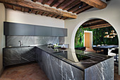 Black marble panels and rustic beams in modern kitchen