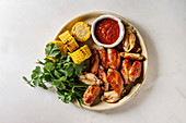 Fried chicken wings with barbecue sauce, grilled corn and cilantro